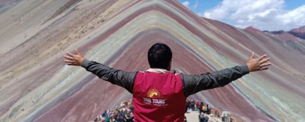 Viajero con casaca de Tari Tours frente a la Montaña de Colores de Vinicunca, Cusco